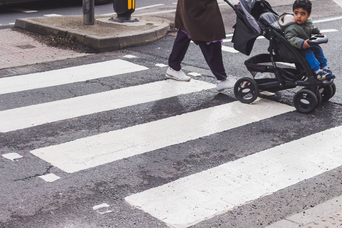 A child in a stroller crossing a zebra crossing in the city