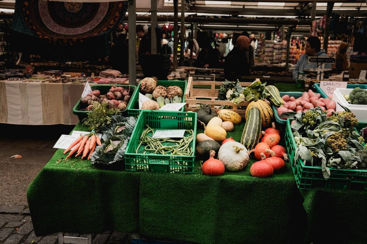 Colorful display of fresh vegetables at an outdoor farmers market stall.