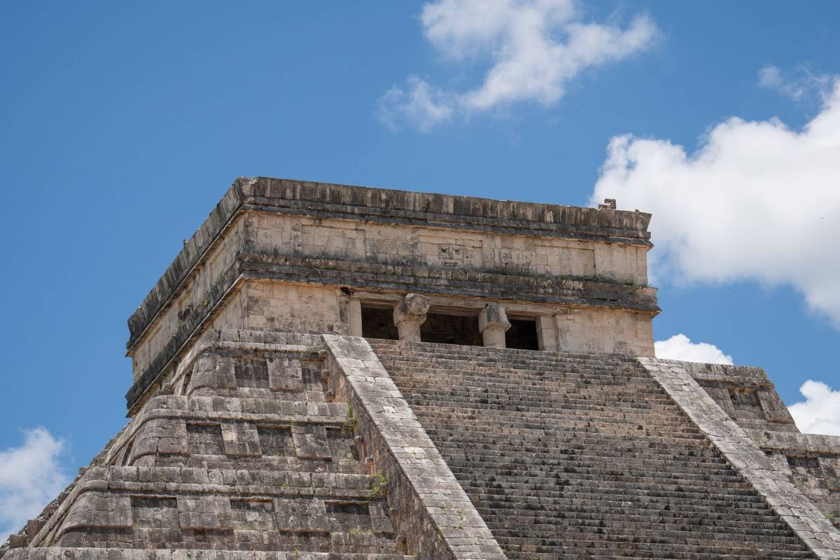 Close-up view of El Castillo pyramid in Chichén Itzá, showcasing ancient Mayan architecture under a vibrant blue sky.