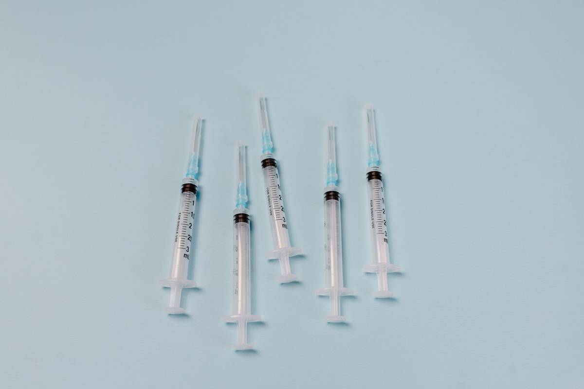 Close-up of sterile syringes arranged on a light blue surface, ideal for medical themes.