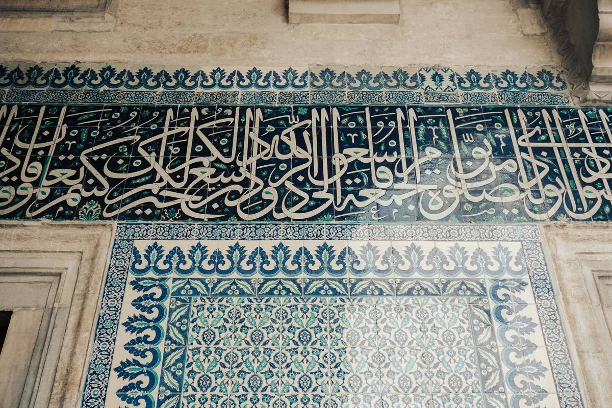 Islamic tile adorned with Arabic calligraphy and geometric patterns.