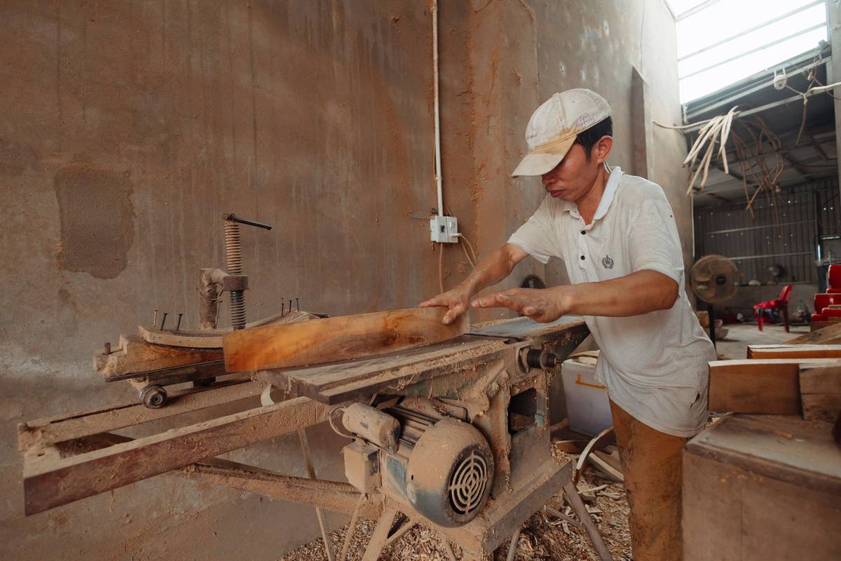 A carpenter cuts wood in a workshop.