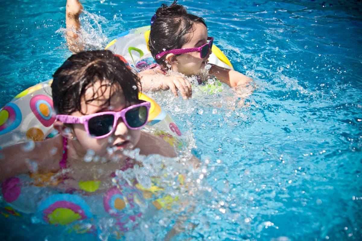 Two young girls enjoying a playful day in a bright blue swimming pool