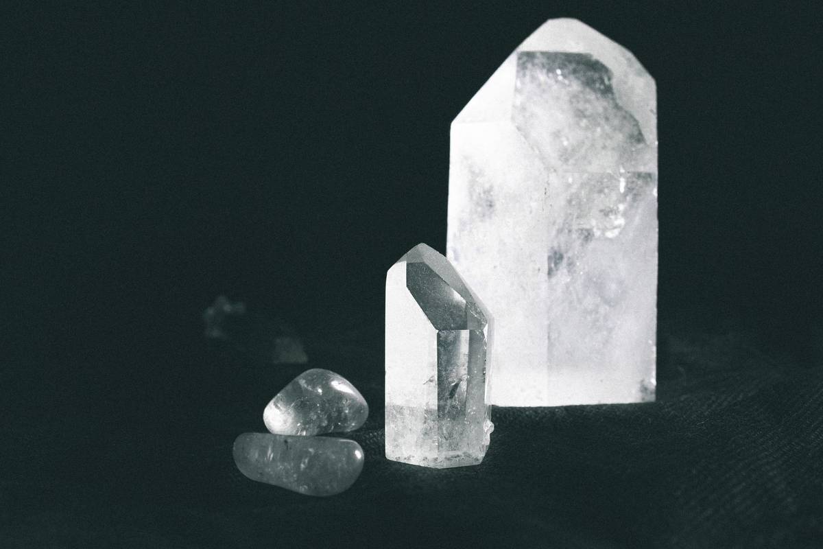 Close-up of various quartz crystals on a dark surface, showcasing their natural beauty.